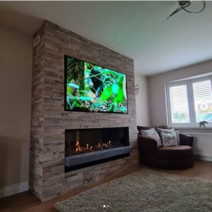 The Bell Horizon balanced flue gas fire with installed into false chimney breast with Tv recess and finished with autumn blend tiled finish Media Wall